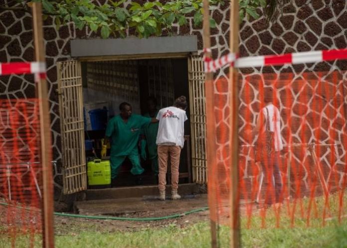 [FILE] An attendant charged to handle the access to the Ebola security zone disinfects hands of a Doctors Without Borders (Medecins sans frontiere - MSF) team member outside the Wangata Reference Hospital in Mbandaka, northwest of DR Congo on May 20, 2018.Three new Ebola cases have been confirmed in the Democratic Republic of Congo's sprawling northwest taking the number of suspected infections to 43, the health minister said in a statement seen on May 19, 2018. / AFP PHOTO / JUNIOR KANNAH