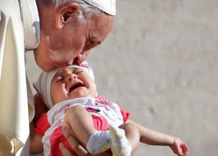 Pope Francis kisses a baby on the forehead as he arrives to lead his weekly general audience at the Saint Peter's square, in Vatican, on September 12, 2018. - AFP PHOTO - Tiziana FABI